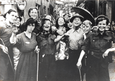 879134 Afbeelding van een grote groep feestvierders in een bevrijdingsoptocht die vanuit de Jacobskerkstraat in Wijk C ...